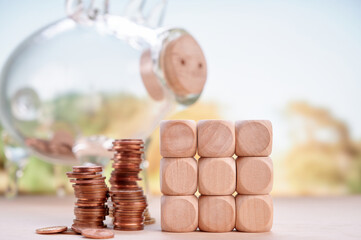 Piggy bank glass with stacked coins and wooden blocks representing savings, financial growth, and...