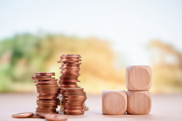 Stacked coins beside wooden blocks showing financial planning, growth, and investment with blurred...