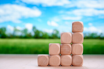Wooden blocks stacked as stairs displaying investment, financial planning, and growth with blurred nature-inspired background emphasizing sustainable and eco-friendly business themes