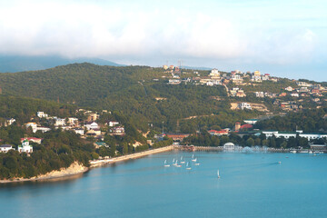 Abrau-Dyurso in September. Picturesque panoramic view of the mountain village, lake and embankment. There are many sailing yachts on the lake.