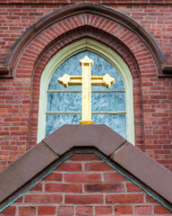 Golden cross and arched window of the historic Saint Mary of the Assumption Parish in Brookline,...