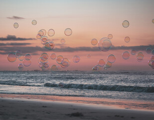 Floating translucent soap bubbles reflecting a sunset beach horizon