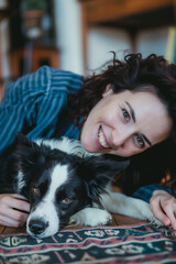 Woman and her dog pose together in a heartwarming moment. The border collie looks up at the camera with love, and the woman smiles.
