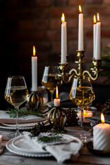 Rustic elegant table decor for christmas family dinner. Center piece with white candle, pine cone, fir tree branches. Zero waste eco-friendly home decoration. Cozy atmosphere, wooden background.