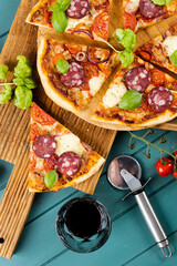 Slices of pizza with sausage on a wooden board and a glass of wine