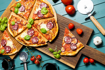Pizza with sausage and pizza knives on oak boards and green background