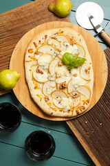 Pizza with a pear on wooden boards