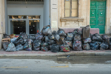 St Julian's, Malta - June 20, 2025: garbage bags overfilling the pavement of a street