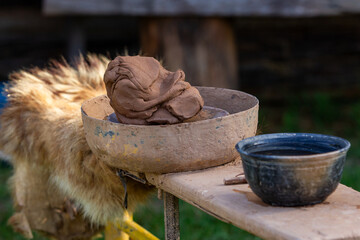 Skilled hands of a potter, covered in clay, expertly shape a pot on a traditional rustic wheel, embodying ancient craftsmanship and the art of pottery creation