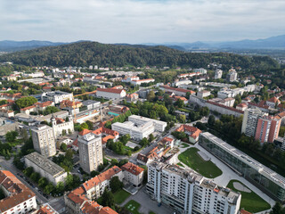 aerial view of ljubljana slovenia (european capital city in europe) castle on hill colorful roofs suburban neighborhood with mountains apartment buildings trees green nature hills river