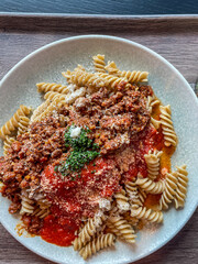 pasta with Bolognese and tomato sauce, parmesan cheese and garnish, top down view, close up, vertical shot