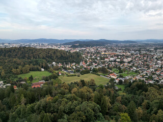aerial view of ljubljana slovenia (european capital city in europe) castle on hill colorful roofs suburban neighborhood with mountains apartment buildings trees green nature hills river