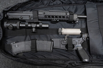 A disassembled modular rifle with accessories, such as an optical scope and a suppressor, neatly...