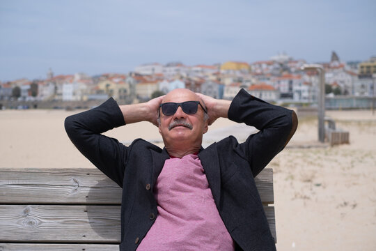 Elderly Man Sitting on Bench on Beach and Relaxing during Vacation in Portugal