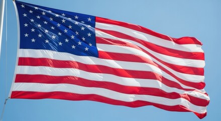 Obraz premium Large American Flag Billowing Against a Bright Blue Sky