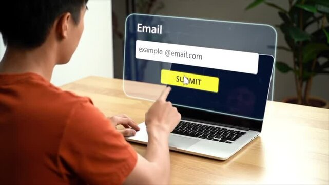 An Asian man interacts with a laptop, entering his email address on a clear screen. He appears focused and engaged in this online process in a modern indoor setting