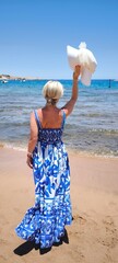 Woman enjoying sea view holding hat in hand