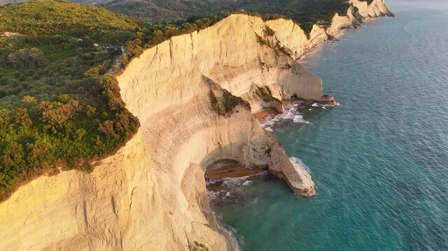 Aerial drone footage of white cliffs and waves at sunset, Cape Drastis Corfu Greece