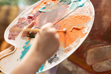 Confident painter mixing different watercolors on a palette to create the perfect dye shade and...