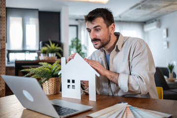Architect showing house model during video call discussing renovation project