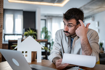 Confused man reading documents and calculating expenses for his new property