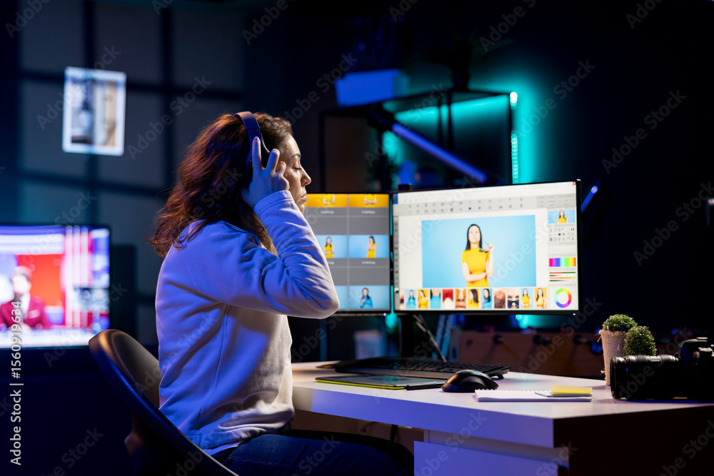 Poster photographer putting headphones on before using retouching program to edit images on computer. photo
