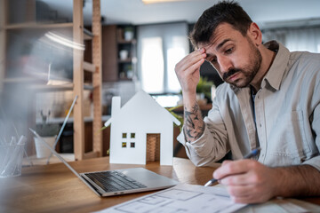 Architect feeling stressed while working at home on blueprint plans