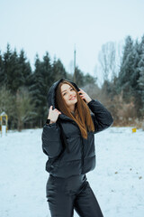 A Joyful Young Woman is Enjoying a Beautiful Winter Wonderland while dressed in a Stylish Black...