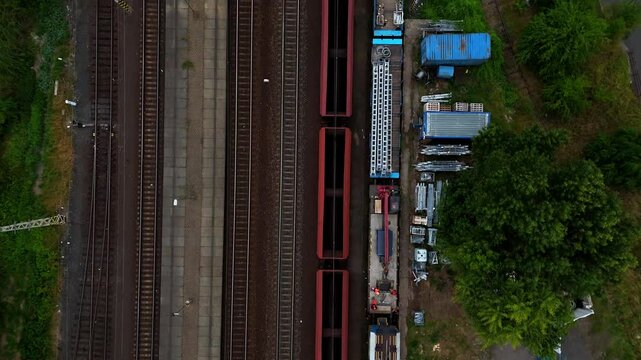 Aerial drone footage of a moving freight train traveling through diverse landscapes. The powerful locomotive pulls cargo cars along winding tracks, showcasing industrial transport and logistics effici