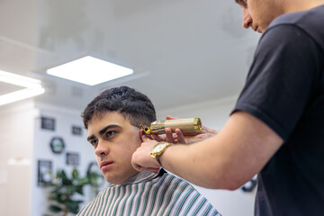 Professional Barber Giving a Haircut to a Young Client with an Electric Trimmer. Young Male Barber...