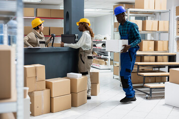Multiethnic employees working together in a logistics center scanning parcels and boxes from the...
