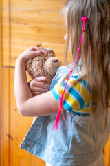 little child, preschool girl 5 years old plays with toy, hugs teddy bear, happy childhood,...