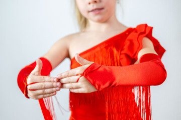5-year-old blonde girl, little aspiring dancer in vibrant red dress performs Latin dance steps,...