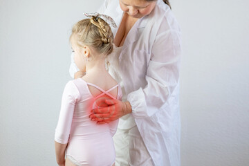 Orthopedist doctor conducts spinal examination child, young girl in ballet leotard shows signs...