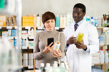 Adult woman buyer scanning qr code for shampoo or shower gel with adult man pharmacist in pharmacy