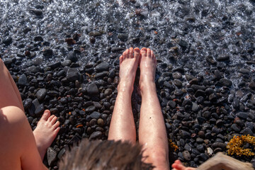 Two children playing on dark rocky beach, teenagers boys play in sea, ocean, family Water...