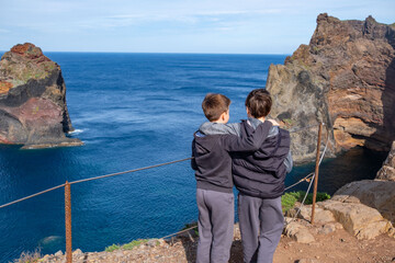 teenagers travelers, boys 10-12 years old gazing at ocean from high trail, peaceful mountain coast...