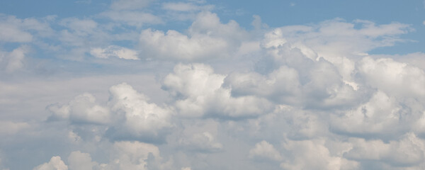 White cumulus clouds are floating across a vibrant blue sky, creating a breathtaking view of nature's artistry and offering a tranquil scene of peace and serenity