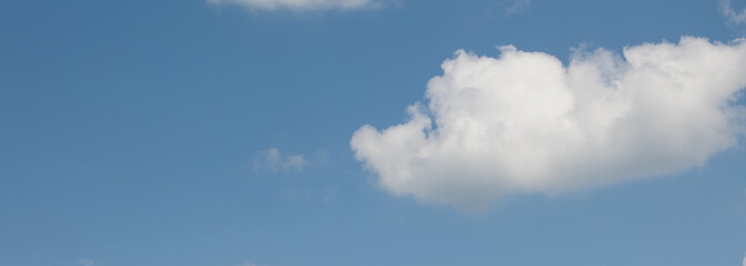 White cumulus clouds gently float across a clear, bright blue sky, creating a serene and peaceful atmosphere, perfect for backgrounds and nature-themed projects