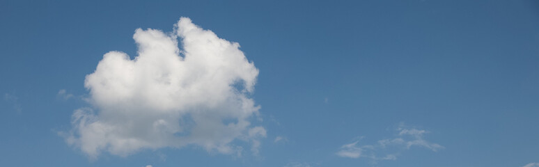 Fluffy white cumulus clouds drifting across a vibrant blue sky, creating a tranquil and serene...