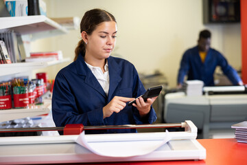Technical worker of printing house calculates cost of payment for work on the calculator