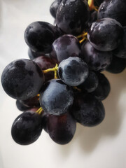 Black grape bunch isolated on white background, photographed in a clean and minimal style for food, fruit, or healthy eating themes.