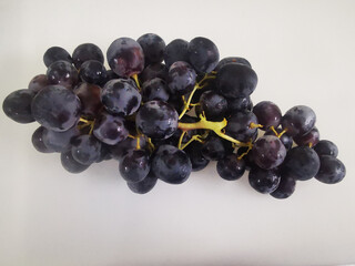 A top-down view of a dark grape bunch placed on a plain white background.