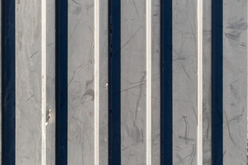 Close-up view of a metal surface featuring vertical stripes that display a worn texture. The light...