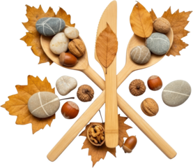 Two wooden spoons and a knife crossed on autumn leaves holding river stones walnuts hazelnuts and acorns