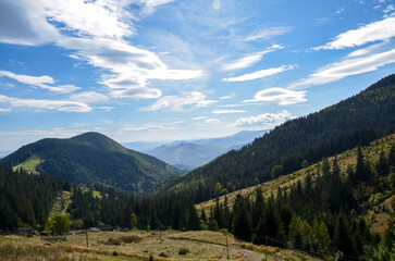 Beautiful mountain scenery featuring forest-covered slopes, a valley between hills, and a partly...