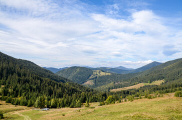 Beautiful mountain scenery featuring forest-covered slopes, a valley between hills, and a partly...