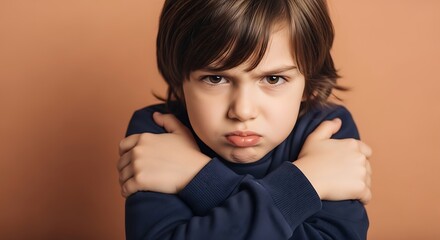 Fototapeta premium Portrait of a young child with a displeased expression arms crossed against a warm orange background creating a sense of discomfort or cold