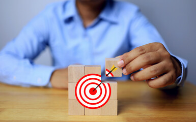 Businessman set goal by arranging wooden dice into dartboard icon conveying the challenge of higher sales targets and making more profit