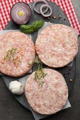 Fresh raw patties for burger and spices on grey table, top view